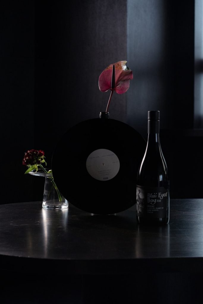 black wine bottle beside red rose